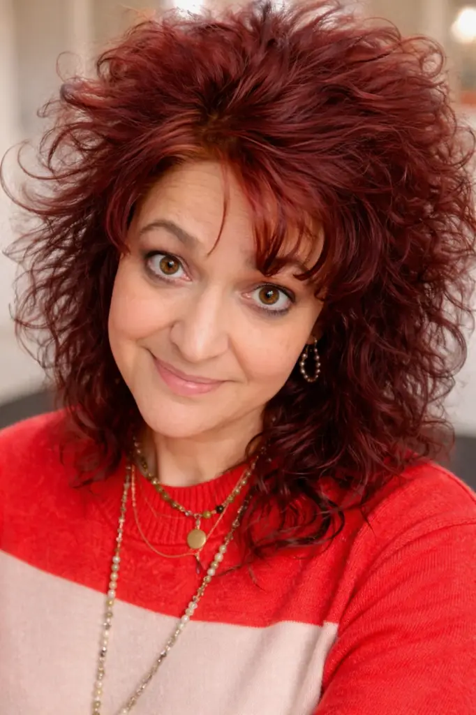 Bridal stylist seated in a wedding dress showroom surrounded by elegant bridal gowns