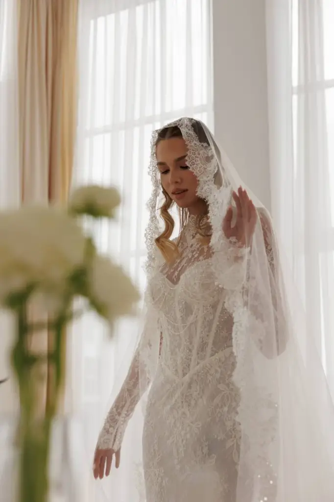 Bride in a long sleeve lace wedding dress with cathedral veil and detailed lace bodice.