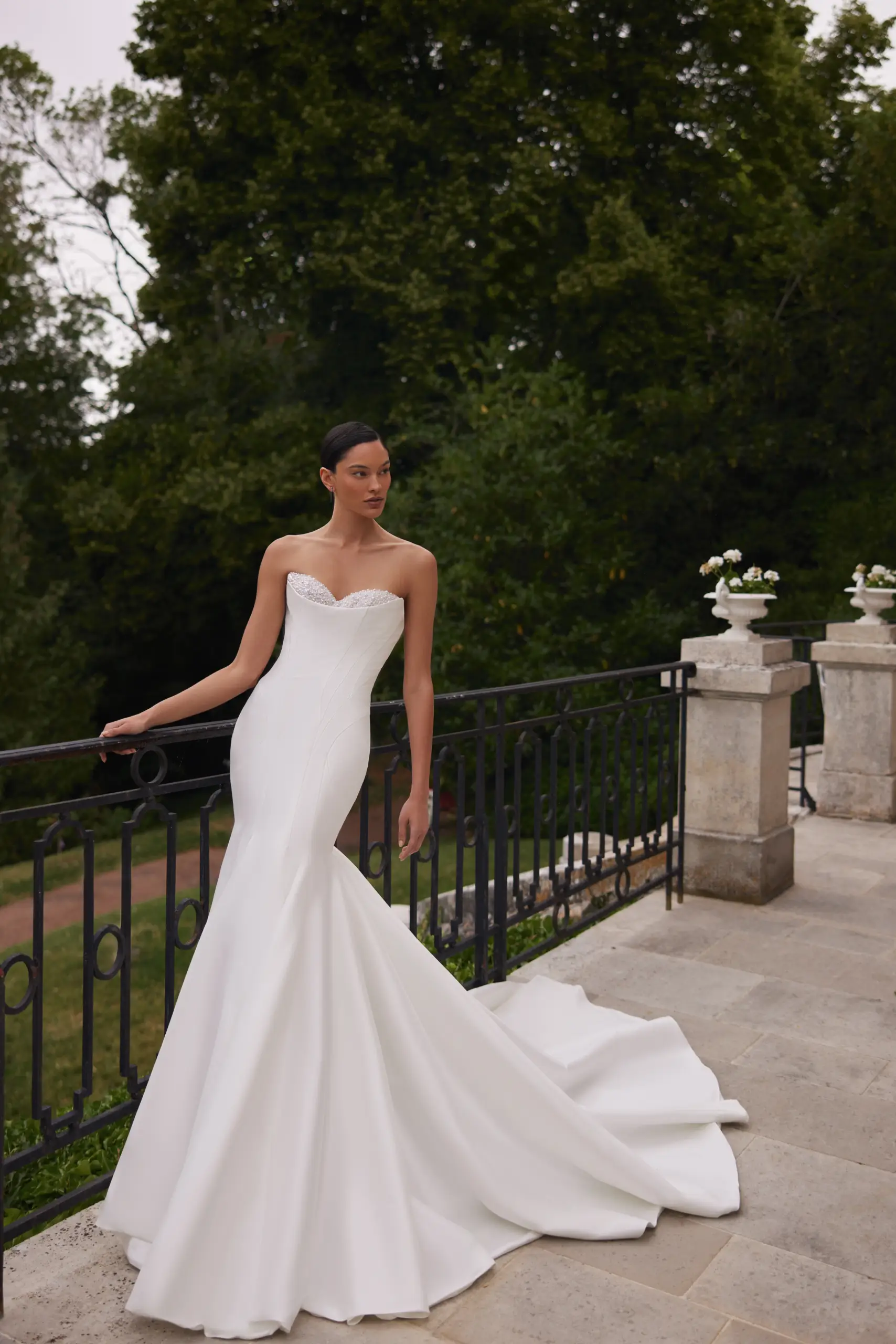 Bride wearing a minimalist strapless mermaid wedding dress with a clean satin silhouette and long train.