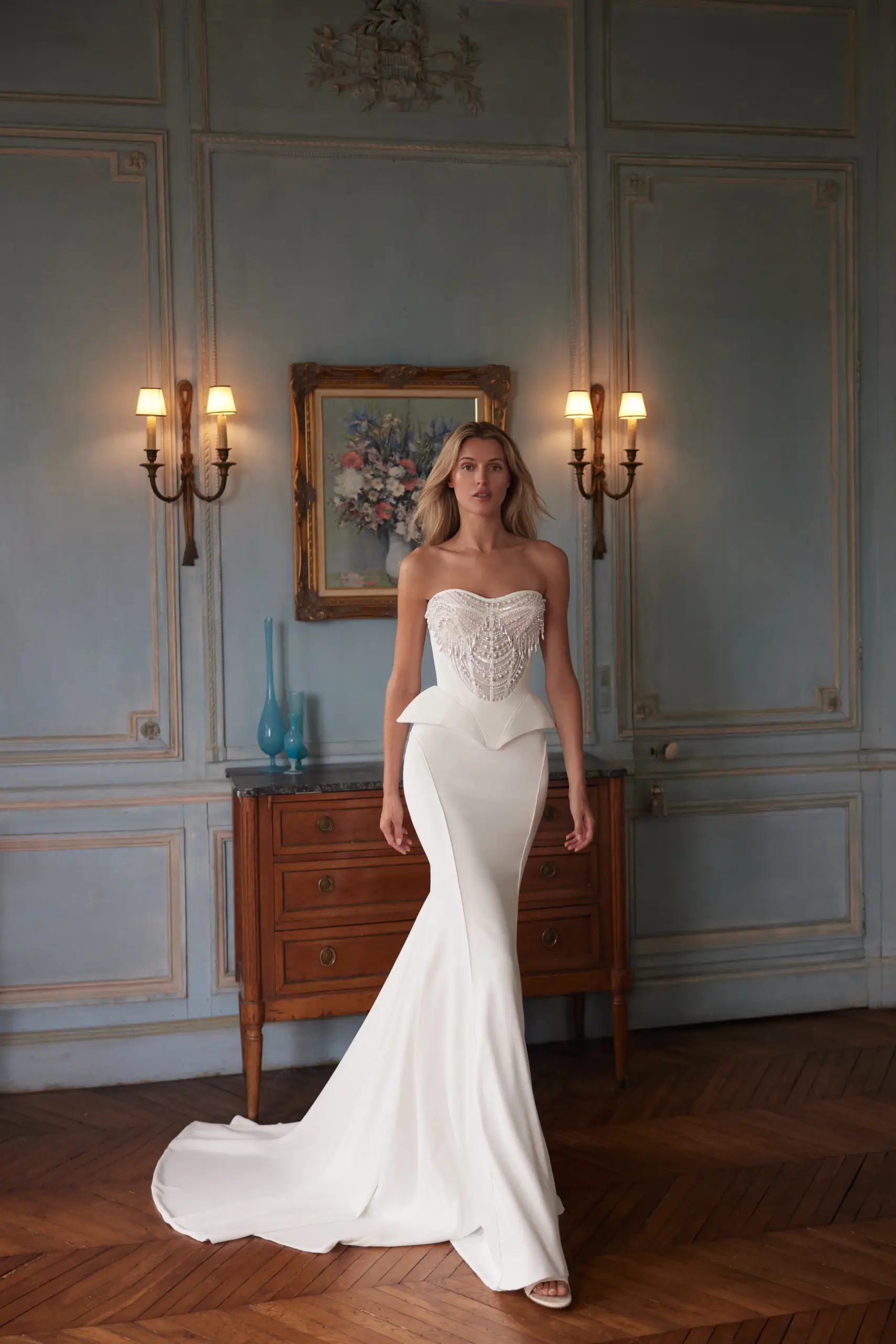 Bride wearing a modern strapless wedding dress with a structured bodice and dramatic peplum detail.